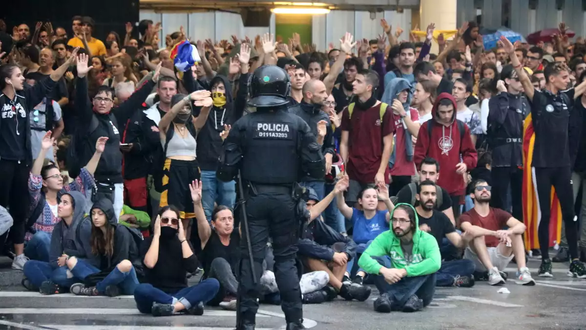 Un grup de manifestants a l'aeroport del Prat convocats per Tsunami Democràtic, darrere d'una línia policial, el 14 d'octubre del 2019