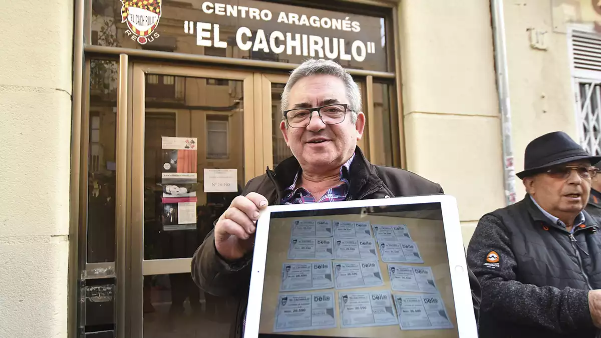 Dioni López mostra les dotze paperetes del primer premi de la Loteria davant d'El Cachirulo