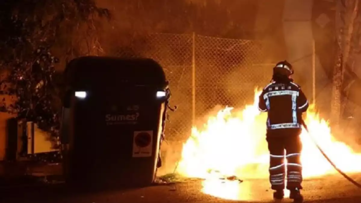 Els Bombers apagant el foc als contenidors que s'han cremat.