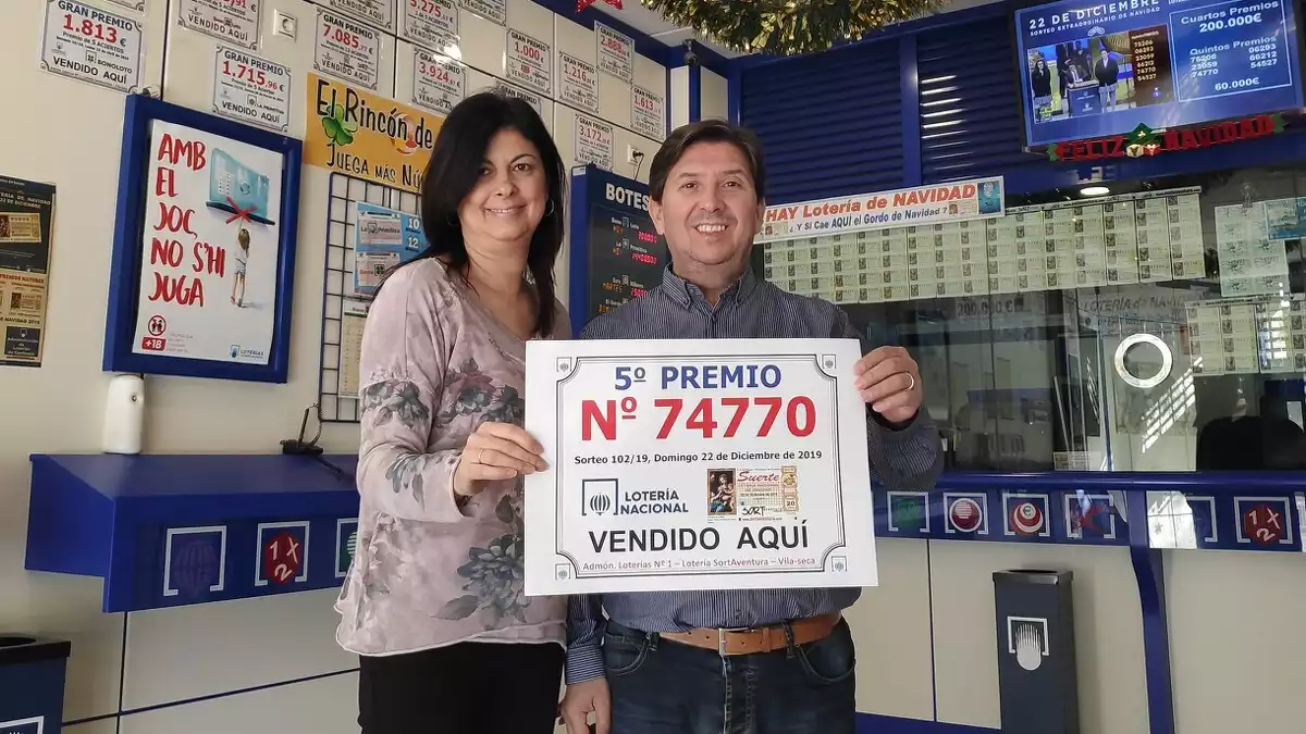 Cristina Cañadas i Rubén Mateos, de l'Administració Sort Aventura de Vila-seca, mostren el cartell amb el número 74770, cinquè premi de la Loteria de Nadal.