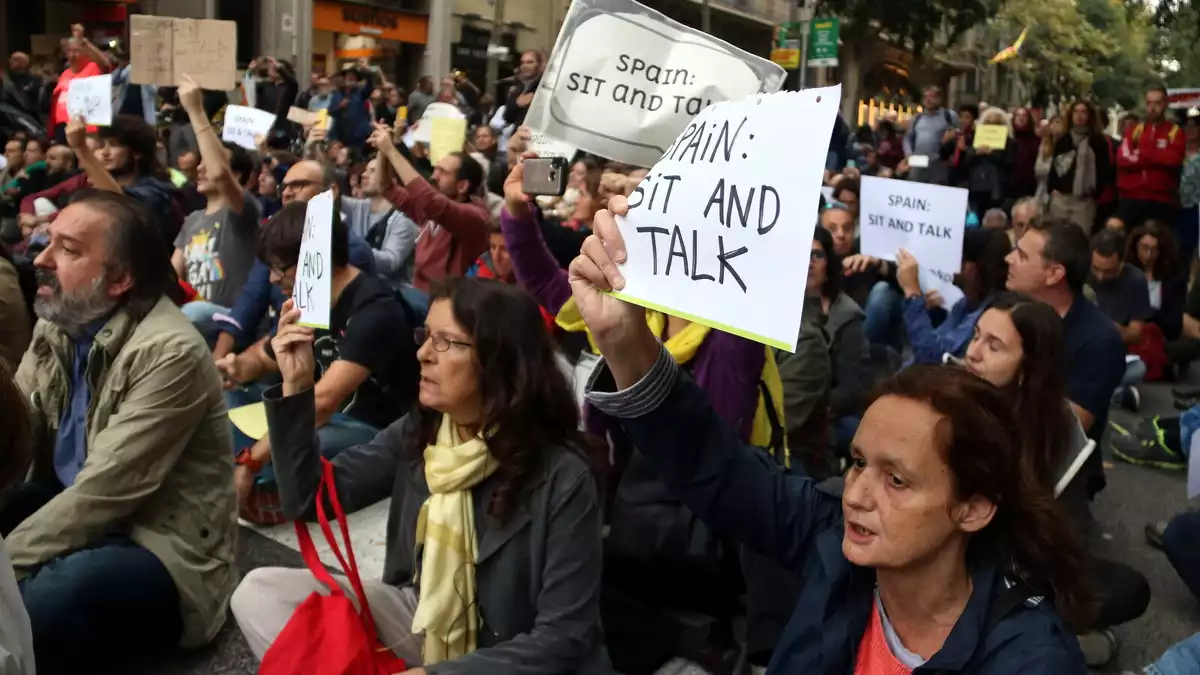 Manifestants asseguts davant la Delegació del govern espanyol amb cartells de 'Sit and Talk' el 21 d'octubre de 2019