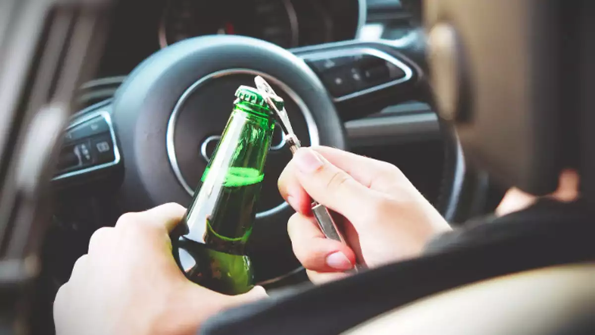 Una persona obrint una cervesa en un cotxe