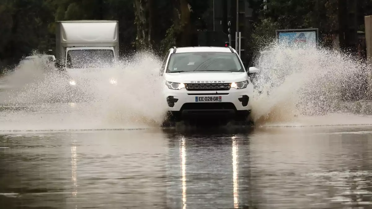 Imatge d'un cotxe enmig d'una carretera inundada