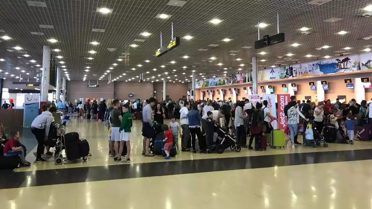 La terminal d'embarcament de l'aeroport de Reus plena de passatgers fent cua per facturar