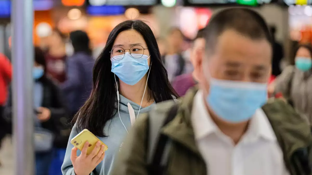 Imatge de dues persones a la xina amb màscara per risc de contraure el coronavirus