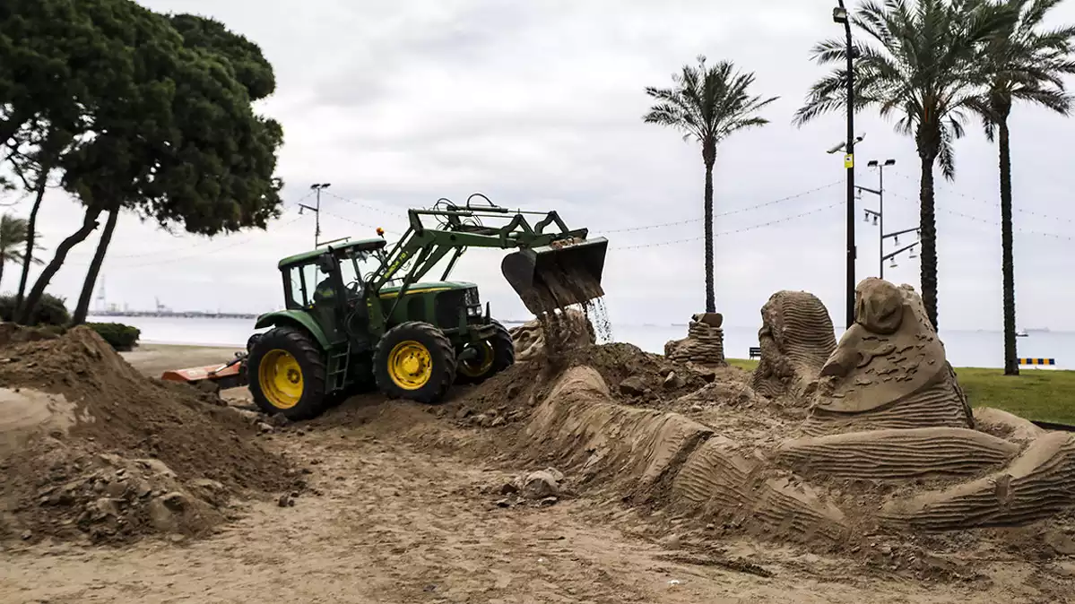 Un tractor de la Brigada Municipal de Vila-seca desmunta les escultures de sorra del pessebre de la platja de la Pineda.