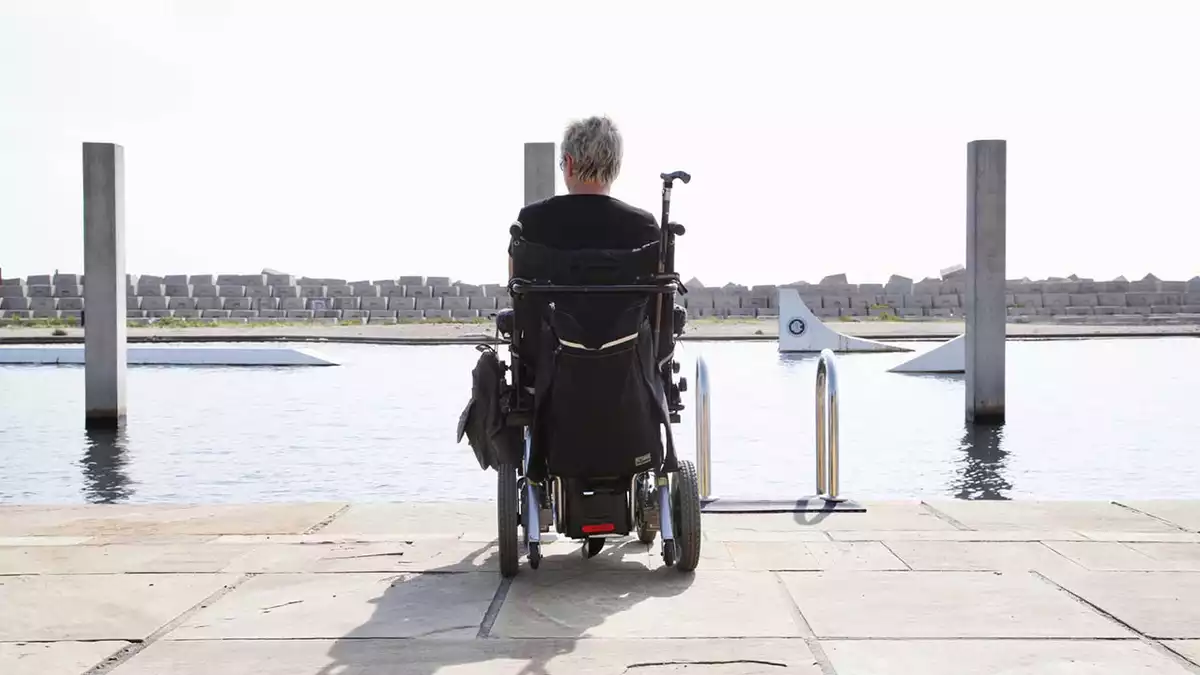 Persona amb cadira de rodes mirant a l'aigua