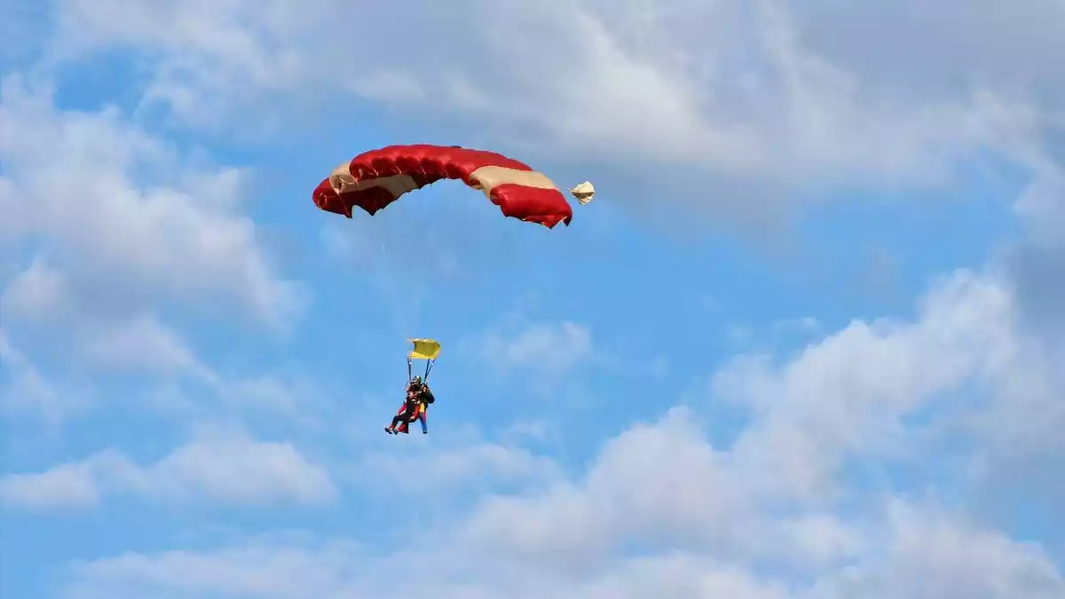 Home en paracaigudes al cel amb un instructor