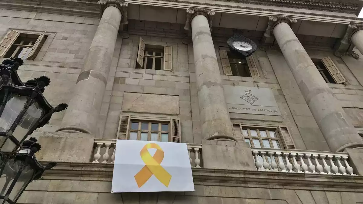 Lona amb el llaç groc penjat al balcó de l'Ajuntament de Barcelona.