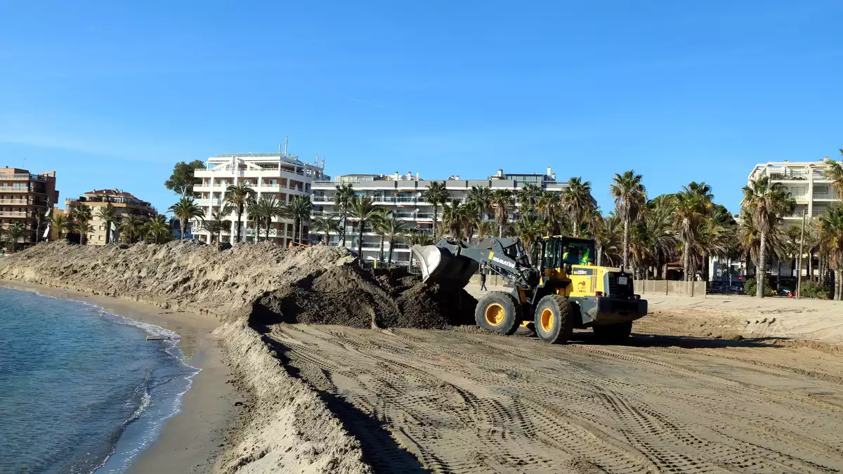 Una excavadora fent un munt de sorra acumulada a la platja de Ponent de Salou, on el temporal Gloria hi va deixar un excedent que s'està trasvasant cap a d'altres platges
