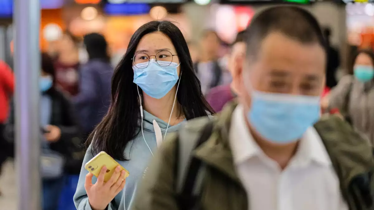Imatge de dues persones a la xina amb màscara per risc de contraure el coronavirus