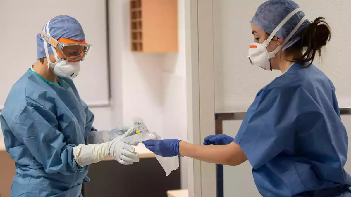 Una professional sanitària entrega una mostar per fer la prova del coronavirus a l'Hospital Clínic