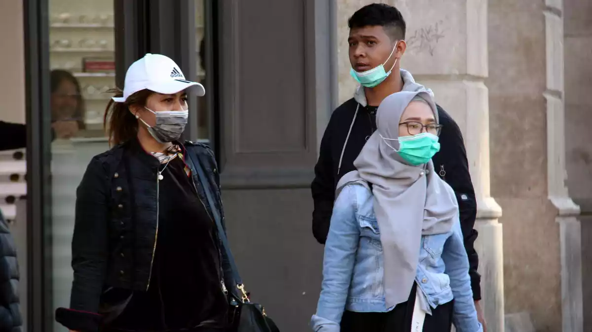 Pla general de ciutadans passejant pels carrers del centre de Barcelona amb mascaretes, l'11 de març del 2020