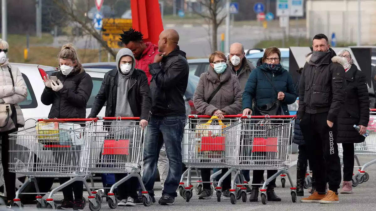 Diverses persones fent cua amb mascaretes a l'exterior d'un supermercat a Casalpusterlengo, el 23 de febrer del 2020
