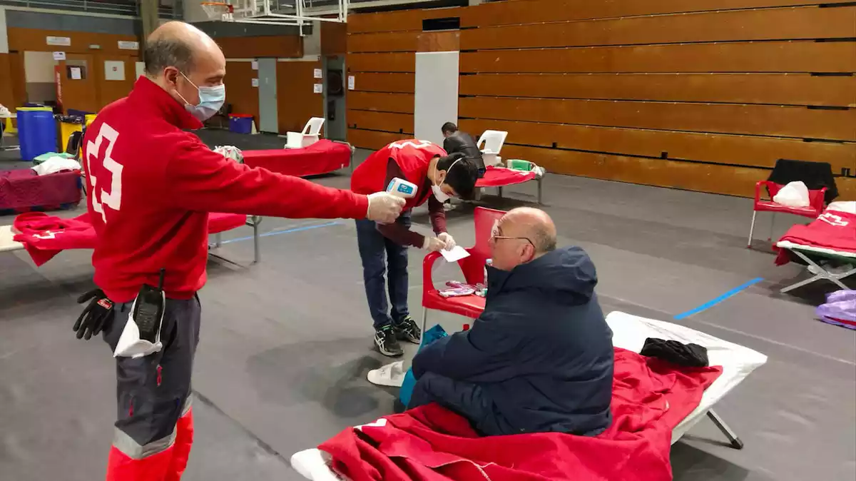 Dos tècnics de Creu Roja atenen un dels confinats a l'alberg temporal del Serrallo