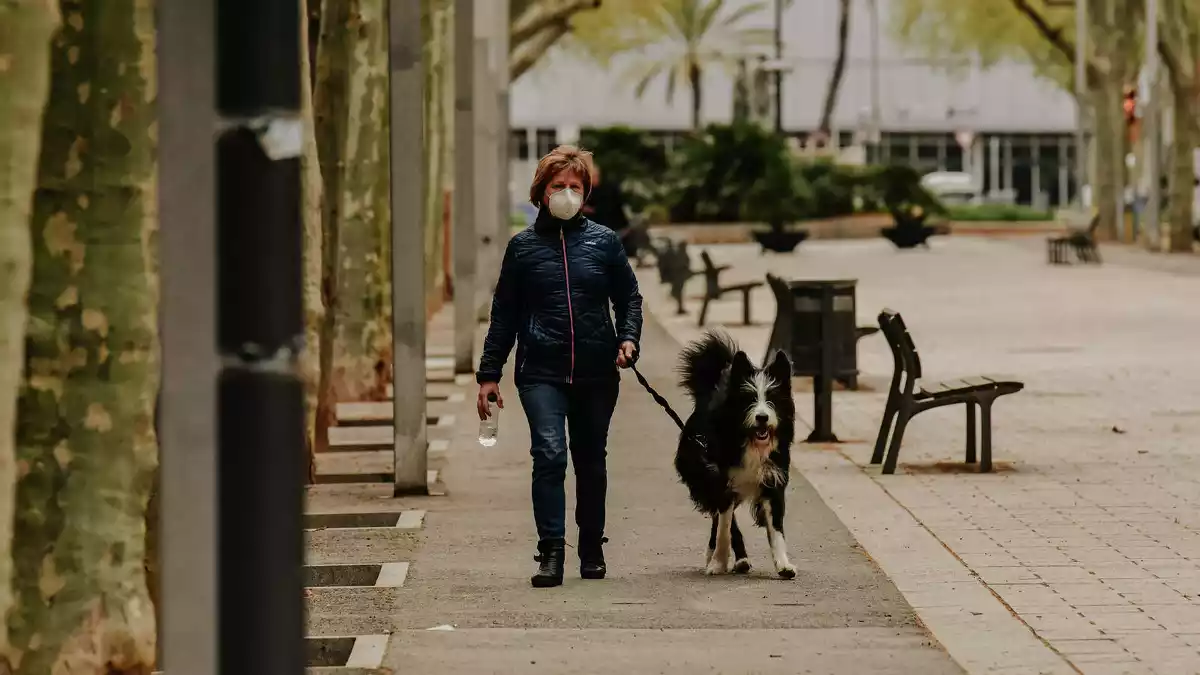 Imatge d'una dona amb mascareta passejant un gos pels carrers de Reus