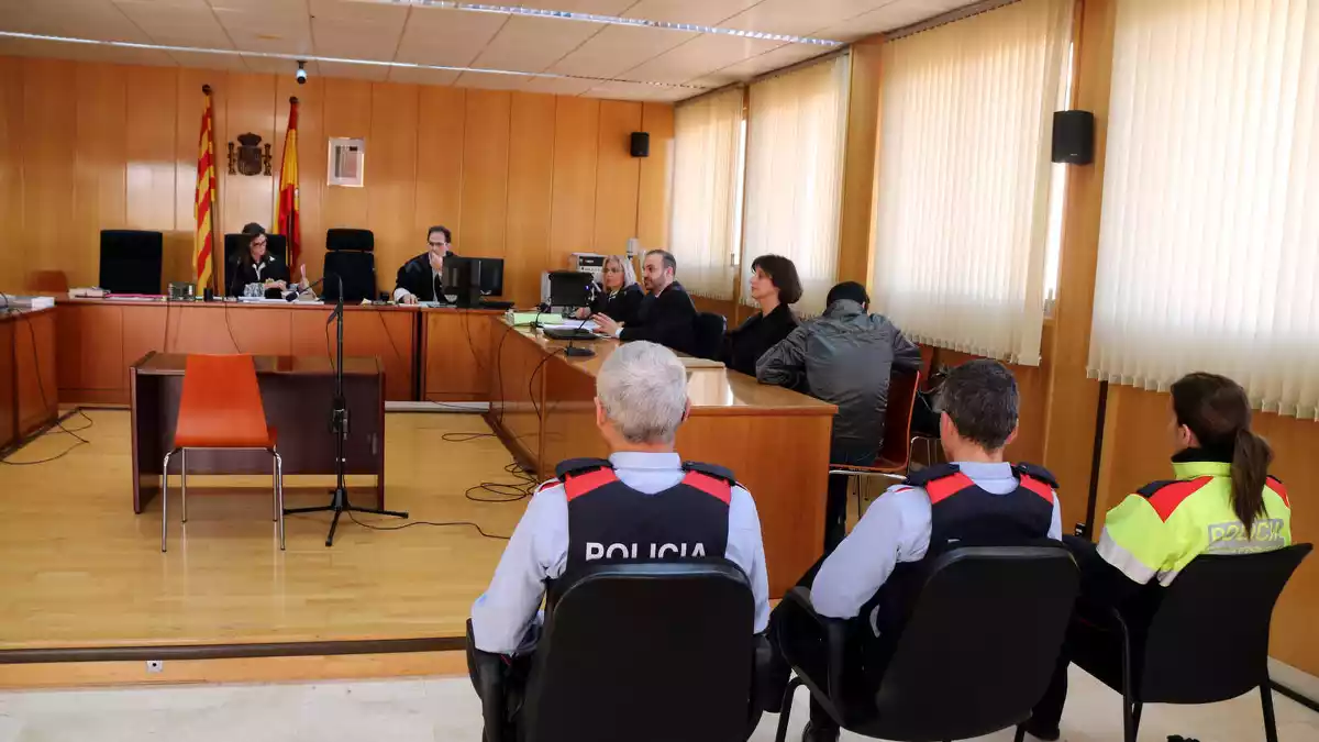 La sala de vistes de l'Audiència de Tarragona, amb tres agents dels Mossos en primer terme, amb l'acusat assegut, d'esquenes, a la dreta