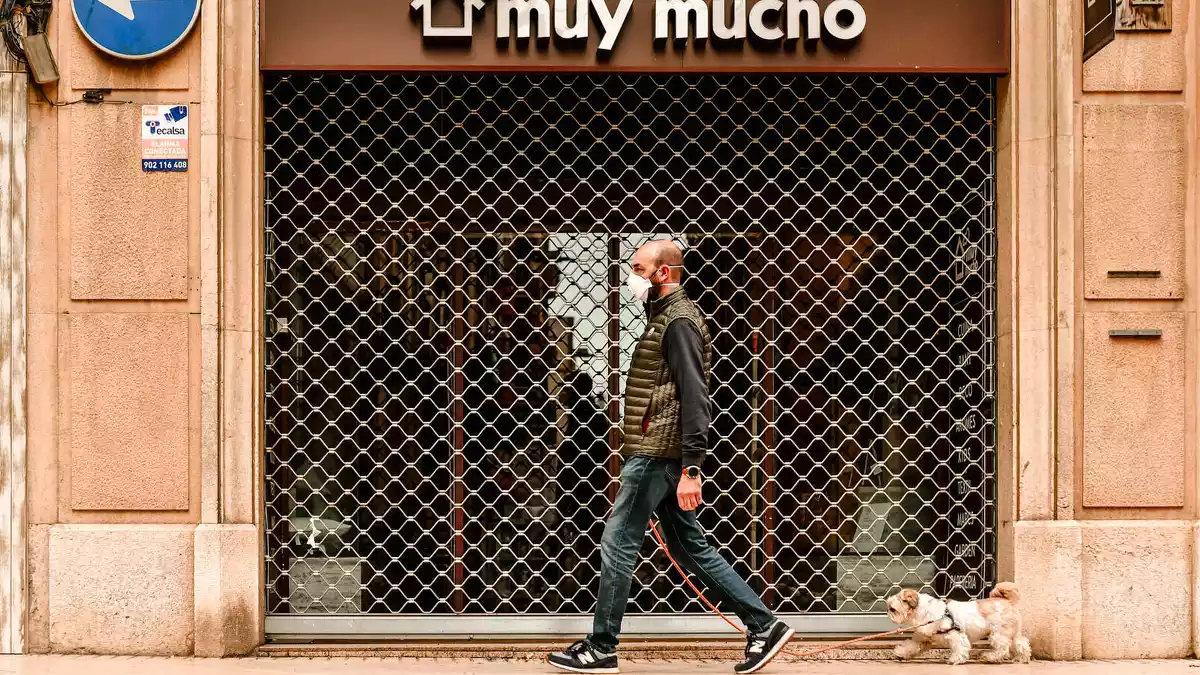 Imatge d'un comerç de Reus tancar durant l'estat d'alarma, amb una persona amb mascareta