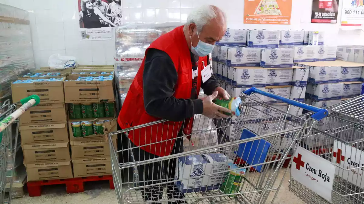 Pla sencer d'un voluntari de Creu Roja Tarragona preparant el carro amb aliments per persones en situació de vulnerabilitat.