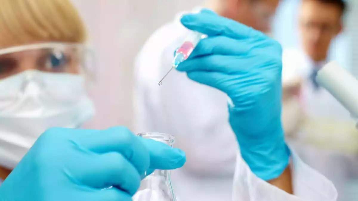 Una científica observa una sustancia que gotea de una jeringuilla