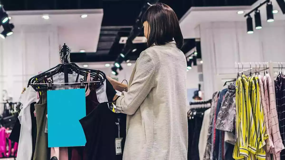 Dona mirant peces de roba en una botiga