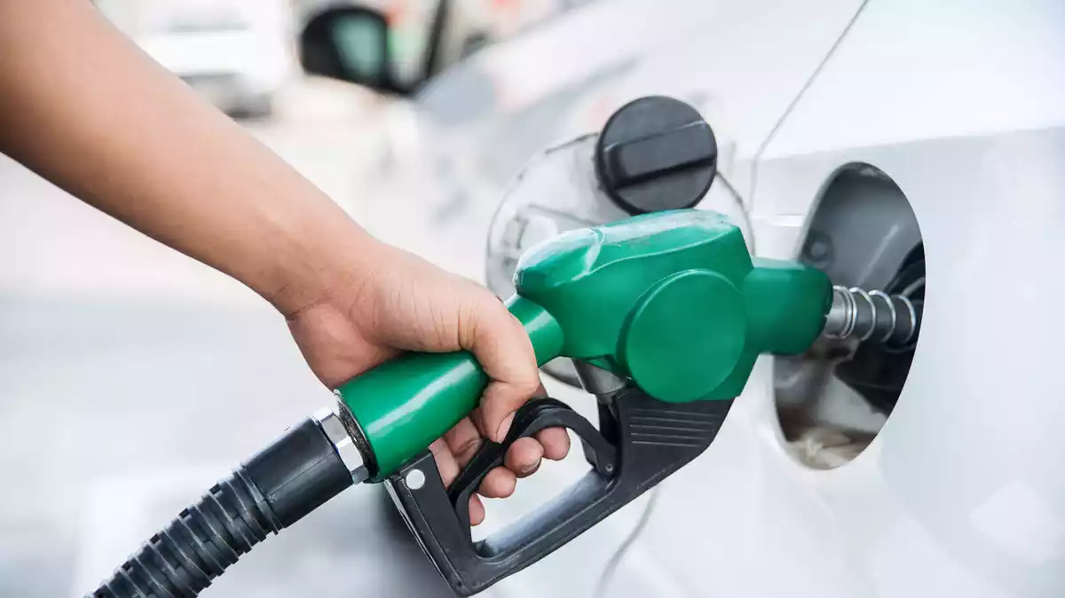 Una persona posant gasolina en un vehicle amb un sortidor de gasolinera
