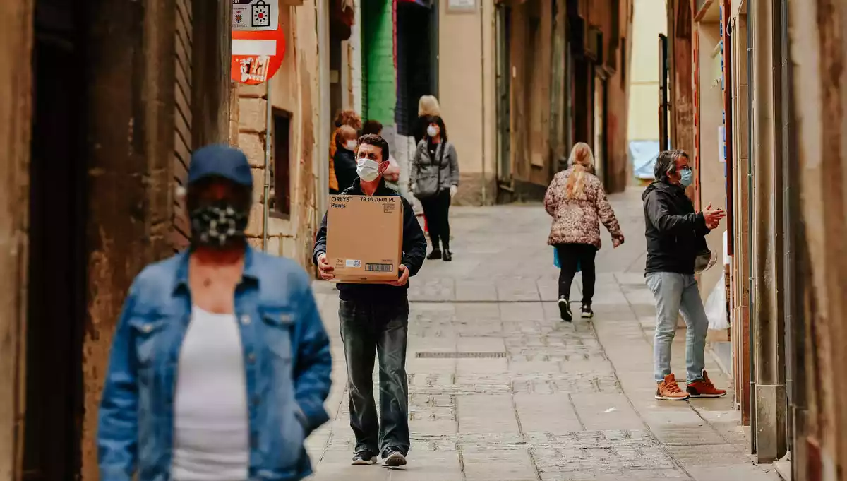 Gent caminant pel carrer amb mascaretes.