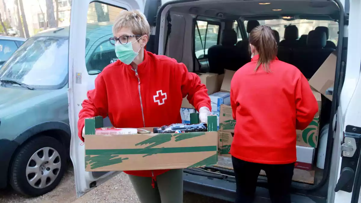 Dos membres de Creu Roja Tarragona treient els aliments de la furgoneta per pujar-los al domicili d'una persona gran, al barri de Sant Salvador