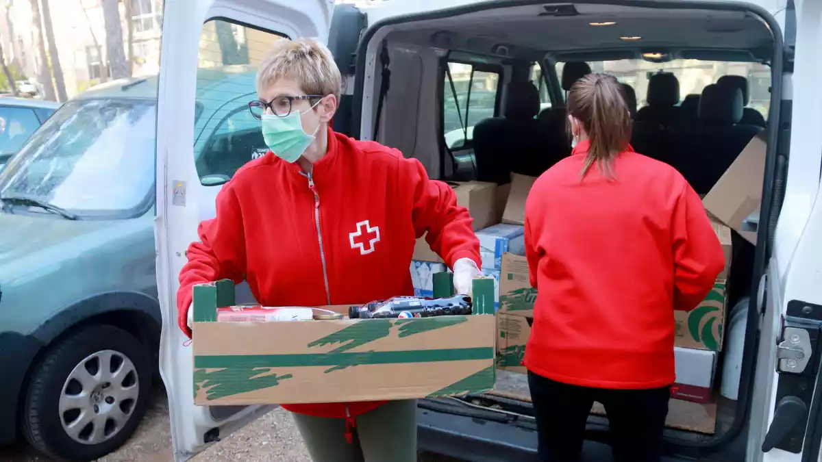 Dos membres de Creu Roja Tarragona treient els aliments de la furgoneta per pujar-los al domicili d'una persona gran, al barri de Sant Salvador