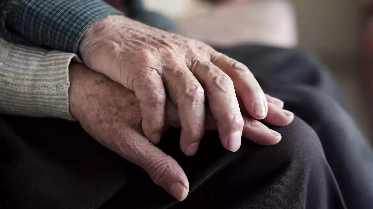 Imagen de la mano de dos ancianos entrelazados entre sí