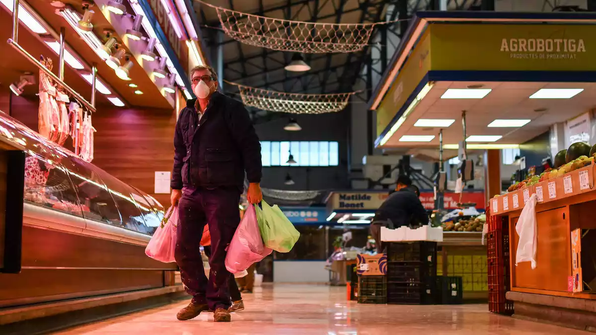 Un home, protegit amb mascareta, compra al Mercat Central de Reus