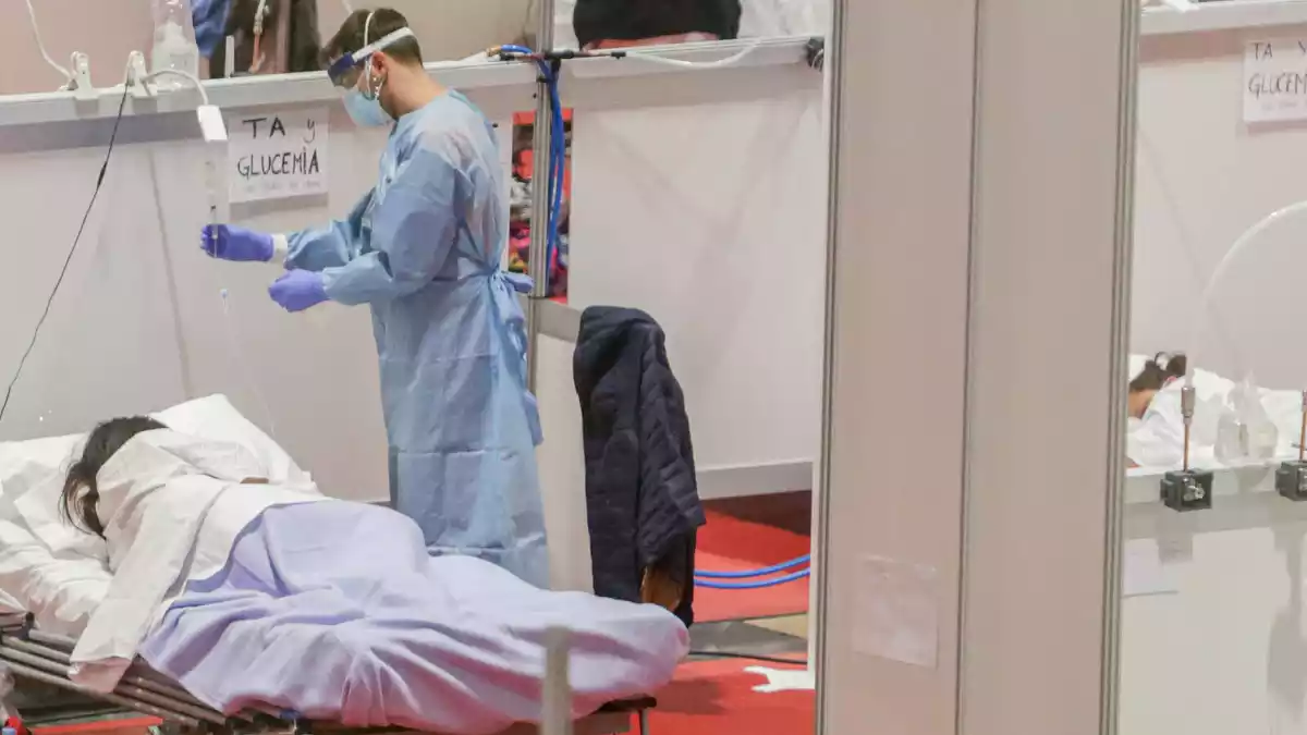 Un sanitario protegido con mascarilla atiende a una paciente ingresada por coronavirus en el Hospital de Campaña montado en el recinto madrileño de IFEMA, en Madrid, el 3 de abril de 2020