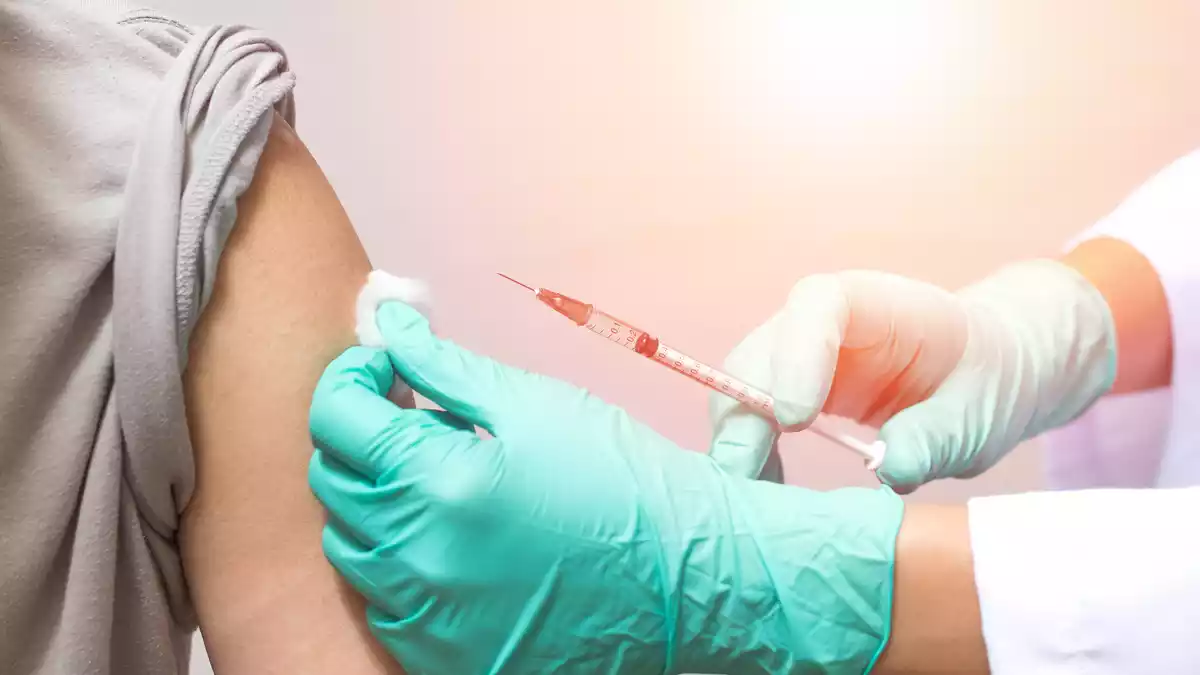 Manos de un doctor poniendo una vacuna en el brazo de un paciente