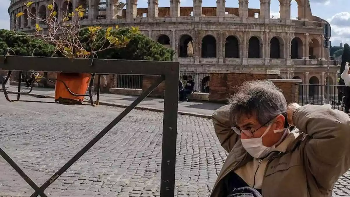 Un hombre se pasea con mascarilla delante del Coliseo en Roma