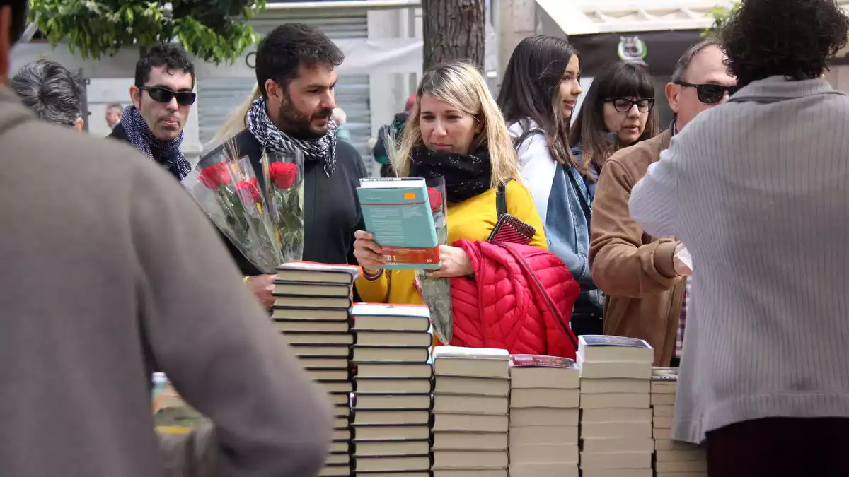 Pla mitjà d'una parella remenant llibres en una de les parades instal·lades a la Rambla Nova de Tarragona per la diada de Sant Jordi de 2019