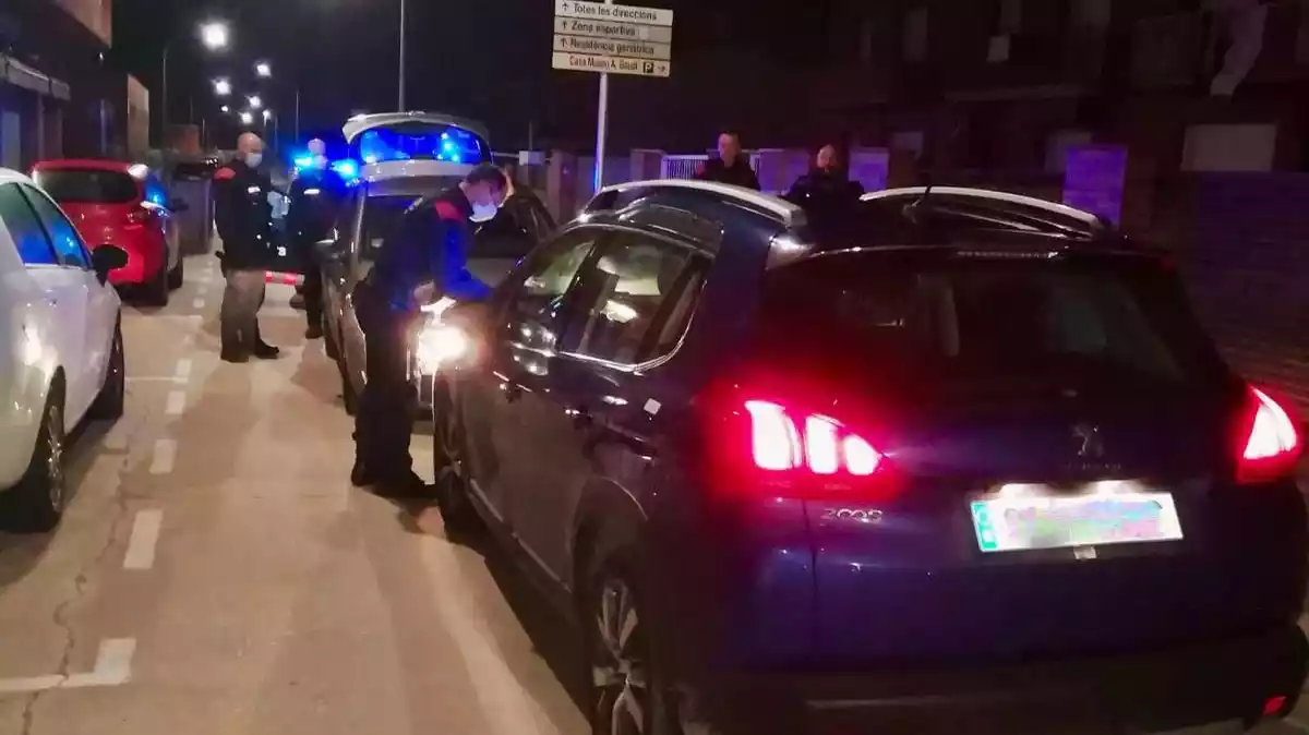 Dos cotxes aturats, de cara, amb agents dels Mossos d'Esquadra a la zona