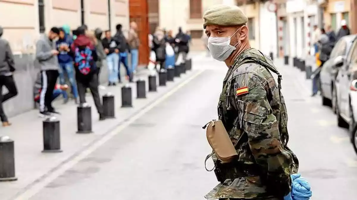 Imagen de un soldado con una mascarilla a pie de calle