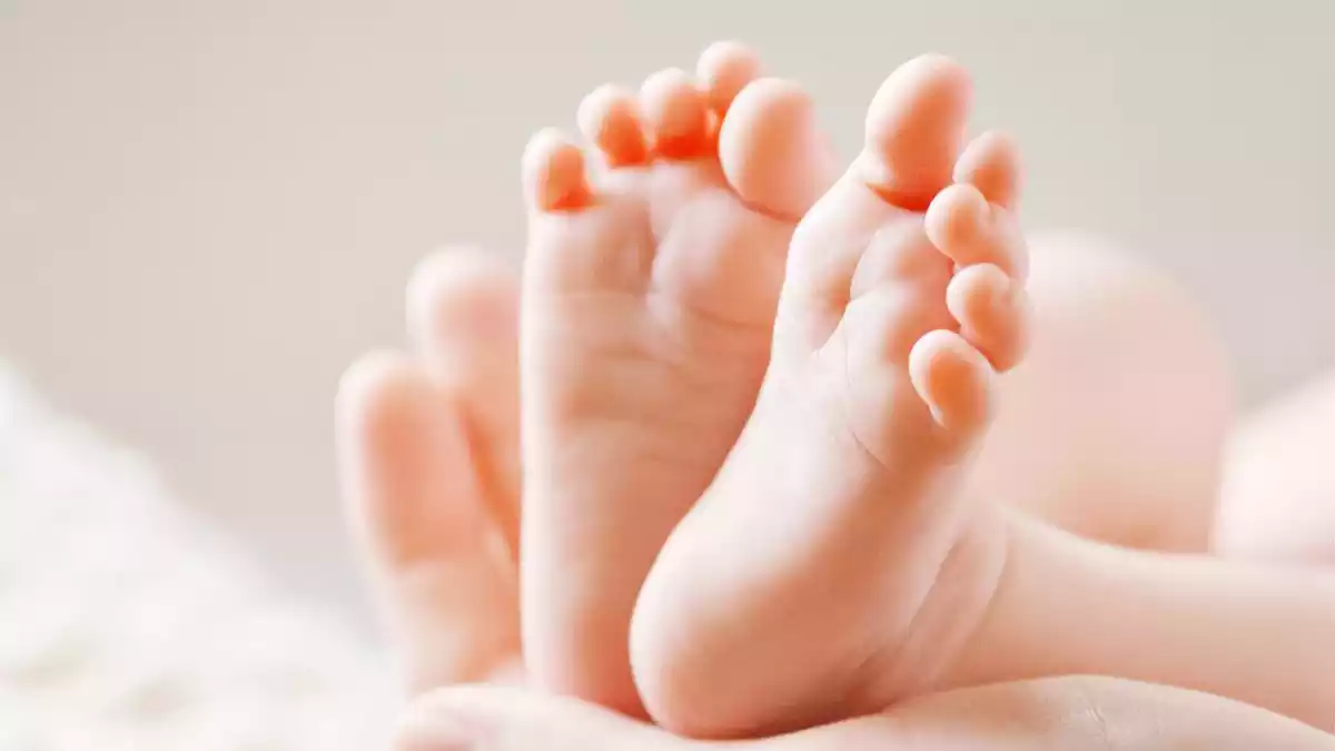 Image de los pies de un bebé abrazados por unas manos