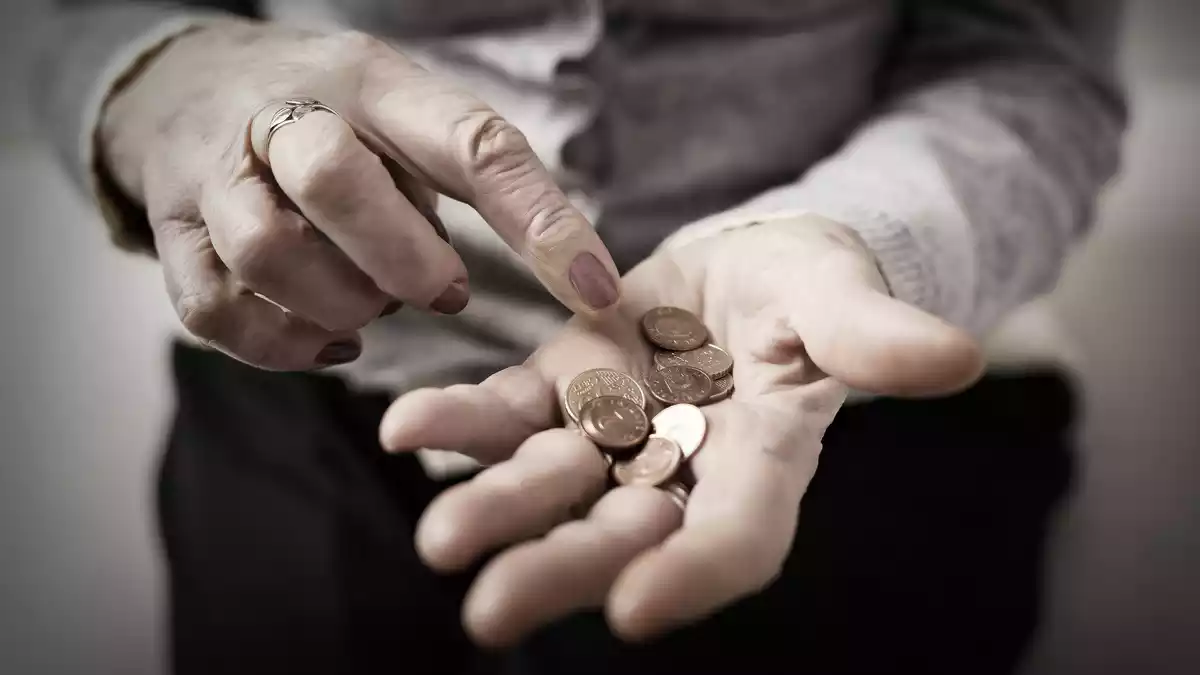 Imagen de una mujer contando las monedas que tiene en la mano