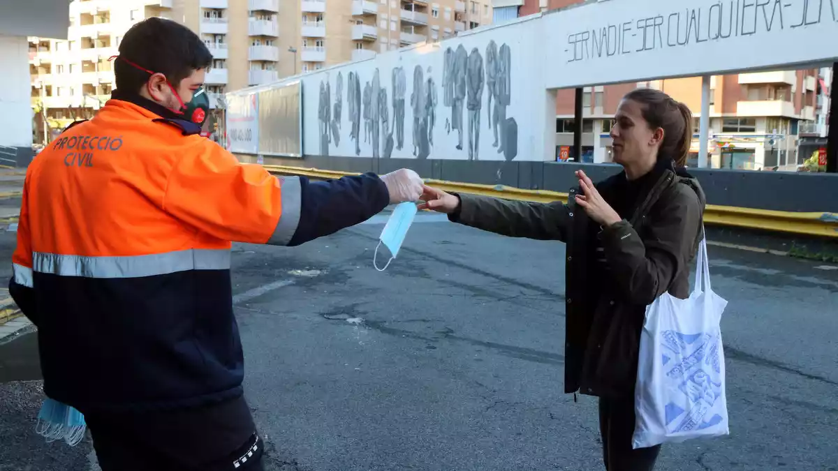 Un voluntari entrega una macareta a una ciutadana