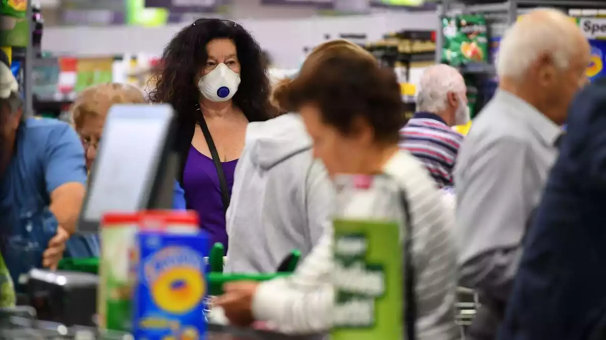 Una dona amb una mascareta comprant en un supermercat