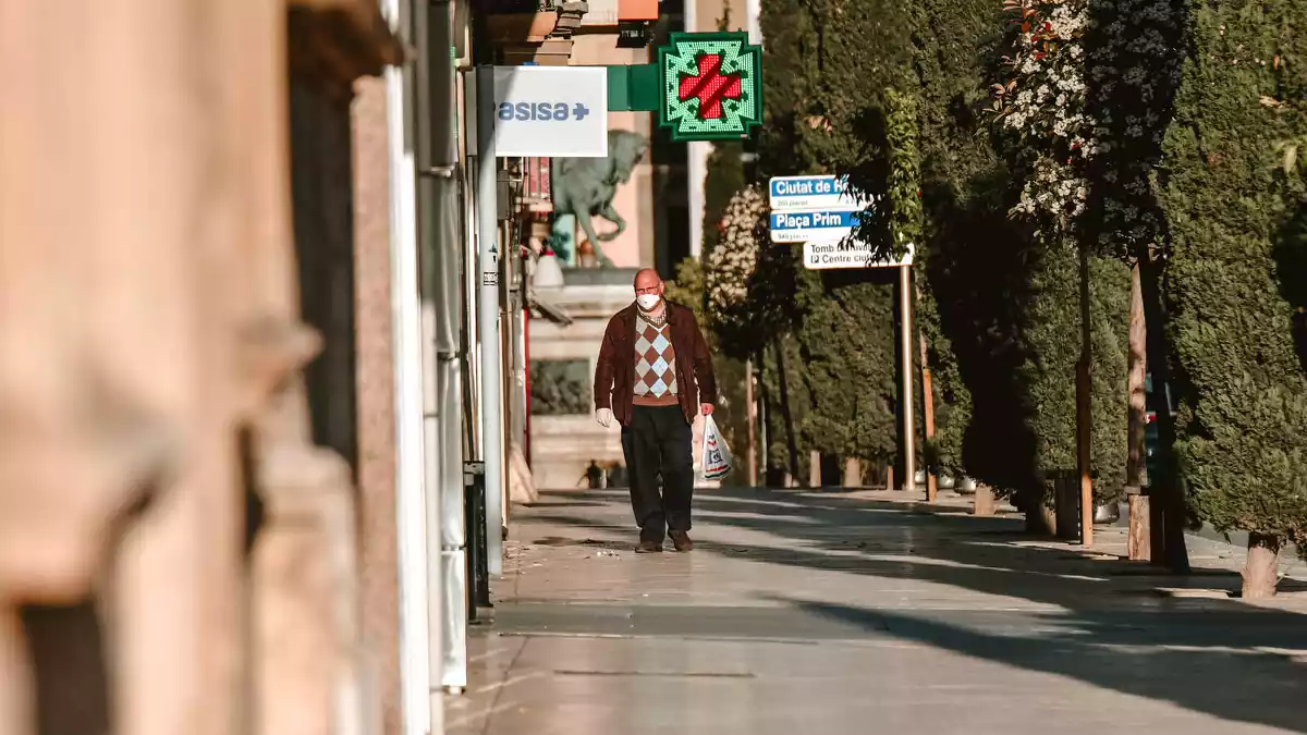 Pla general d'un home amb mascareta caminant per un carrer a Reus