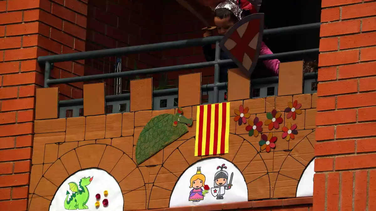 Pla contrapicat d'un nen disfressat de cavaller Sant Jordi al seu balcó engalanat per a la Diada a Tortosa