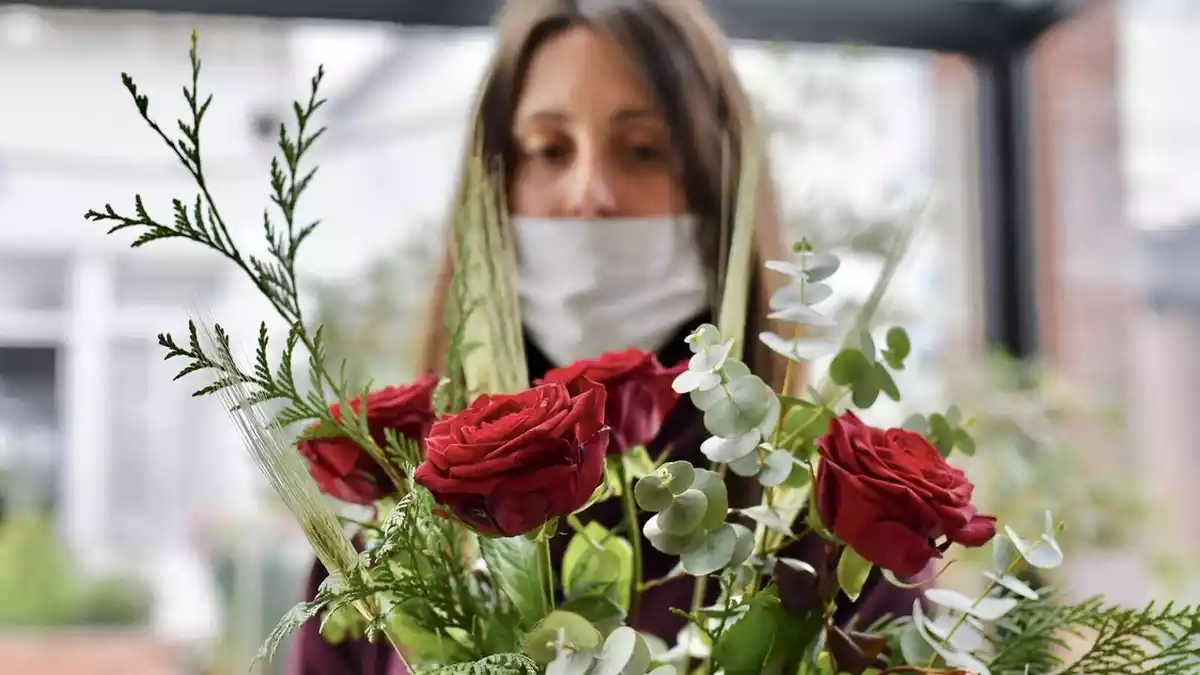 Una florista amb mascareta arregla roses de Sant Jordi