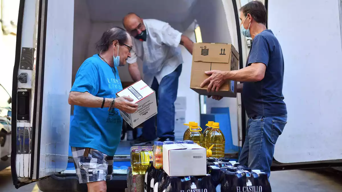 Voluntaris del Banc dels Aliments equipats amb mascaretes descarreguen una furgoneta
