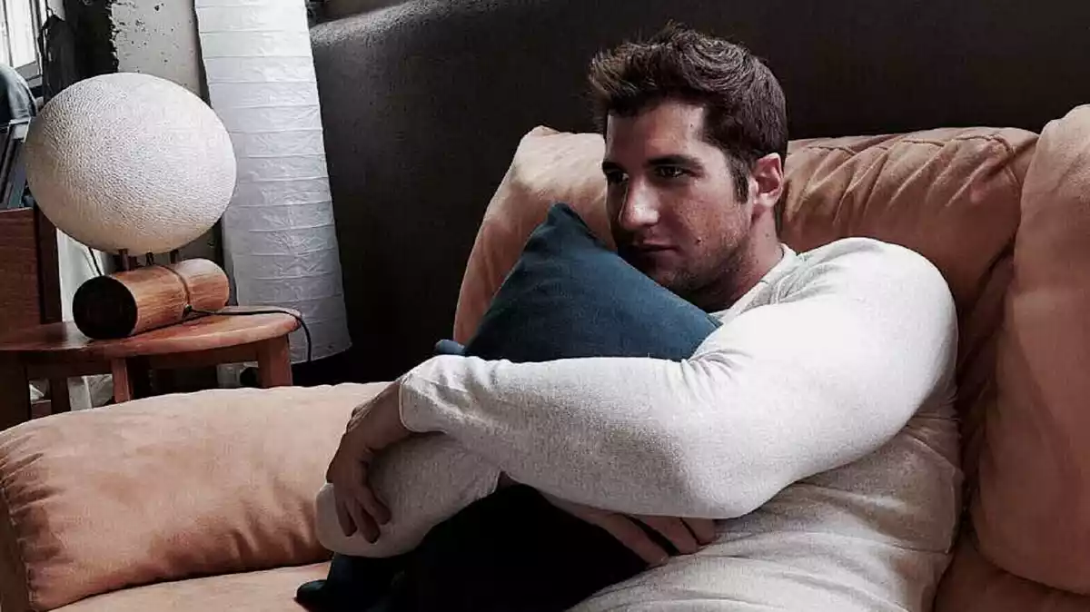 Julián Contreras en e sofá de su casa abrazando un cojín