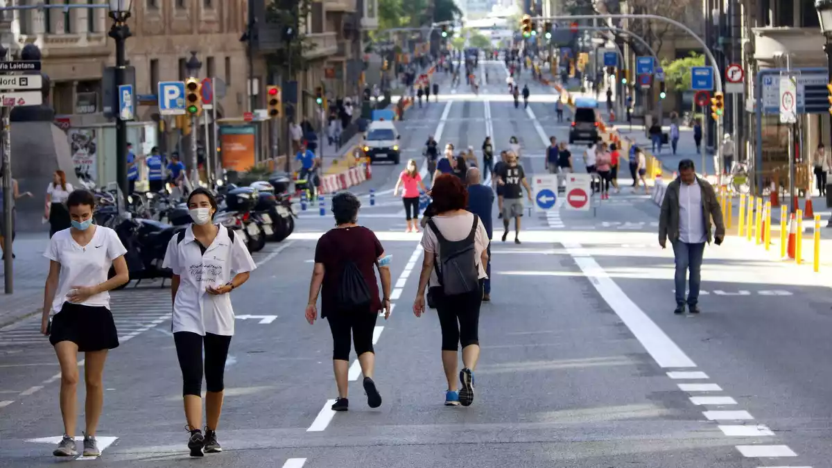 Ciutadans passejant per Via Laietana amb distància de seguretat pel coronavirus, tallada al trànsit, 23/05/2020