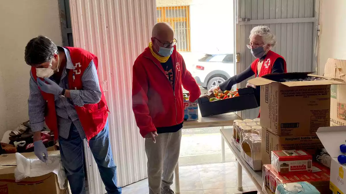 Voluntaris de Creu Roja d'Amposta preparant caixes amb productes alimentaris i d'higienes per repartir entre les famílies més vulnerables de la ciutat.