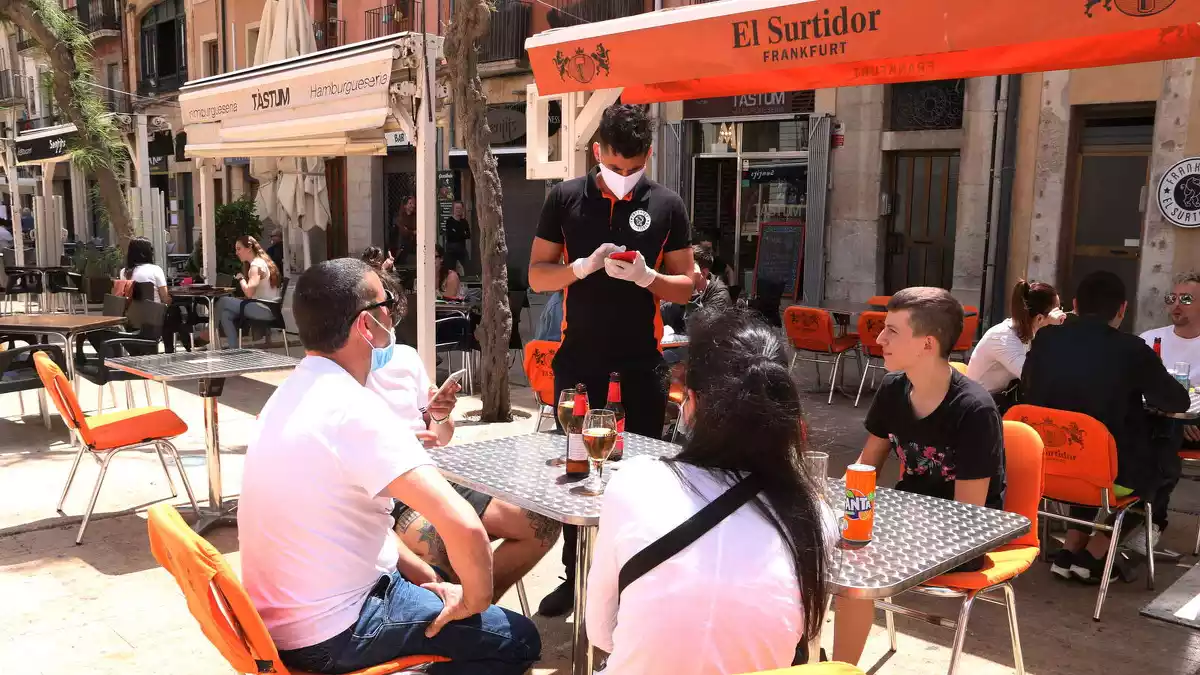 Pla obert d'un cambrer anotant la comada a uns clients en una terrassa de la plaça de la Font de Tarragona en el primer dissabte de la fase 1.