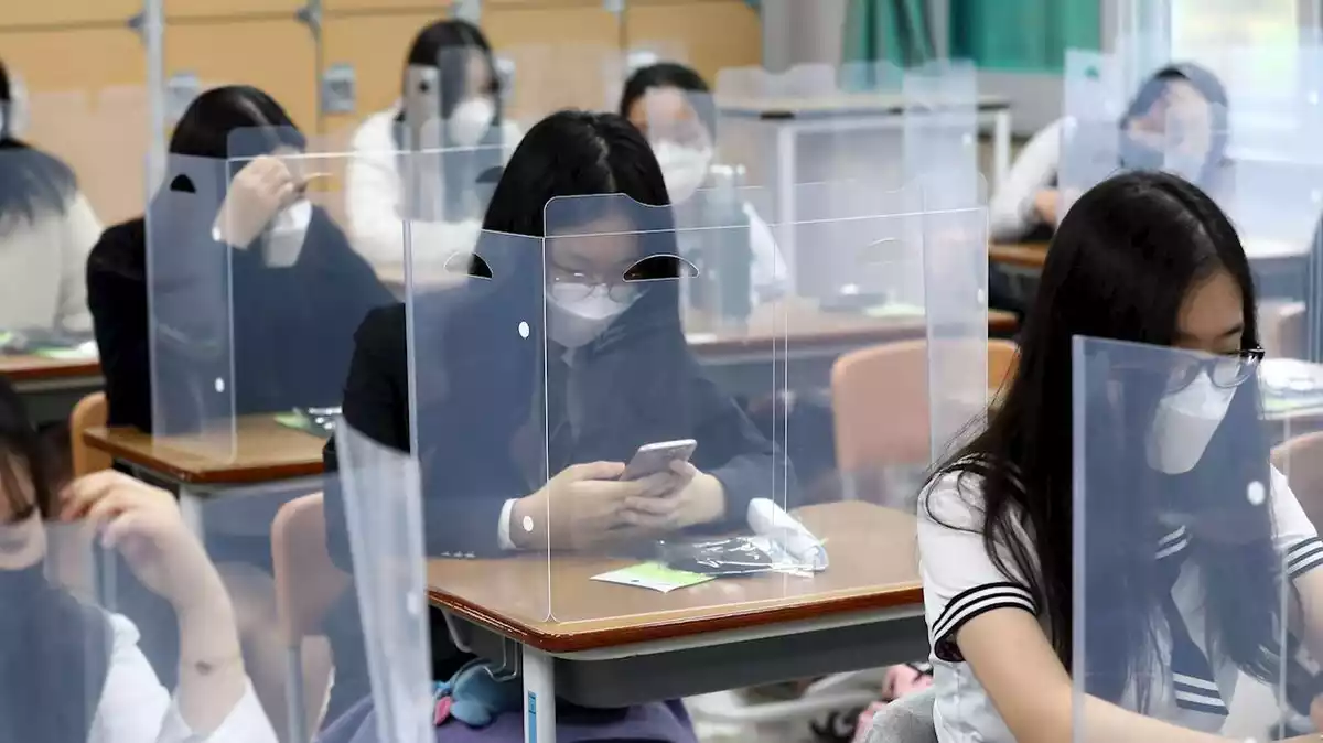 Imatge d'un alumnes de batxillerat en una escola de Corea del Sud, amb les taules protegides per làmines de plàstic